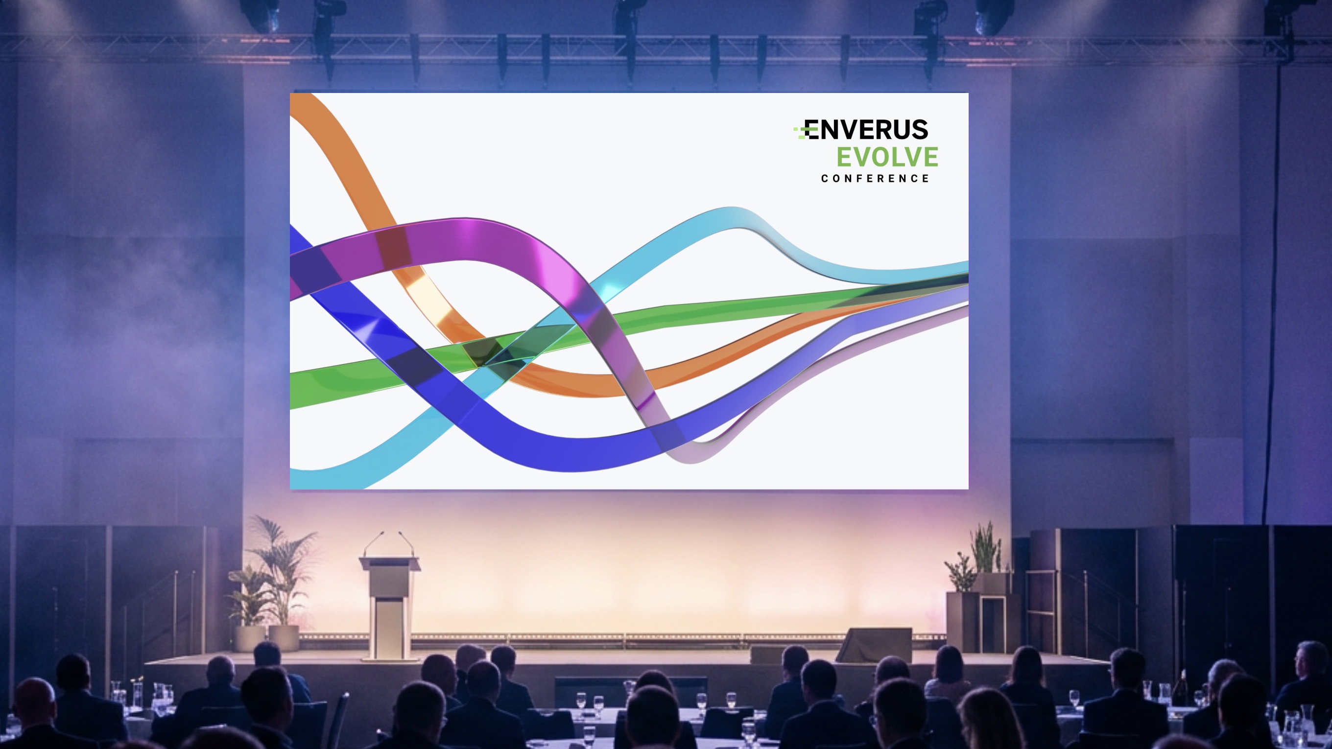 The Evolve 2025 key visual on the keynote stage screen: green, blue, orange and purple 3D ribbons flowing across a white field under the Enverus Evolve Conference logo, above a podium and a seated audience.